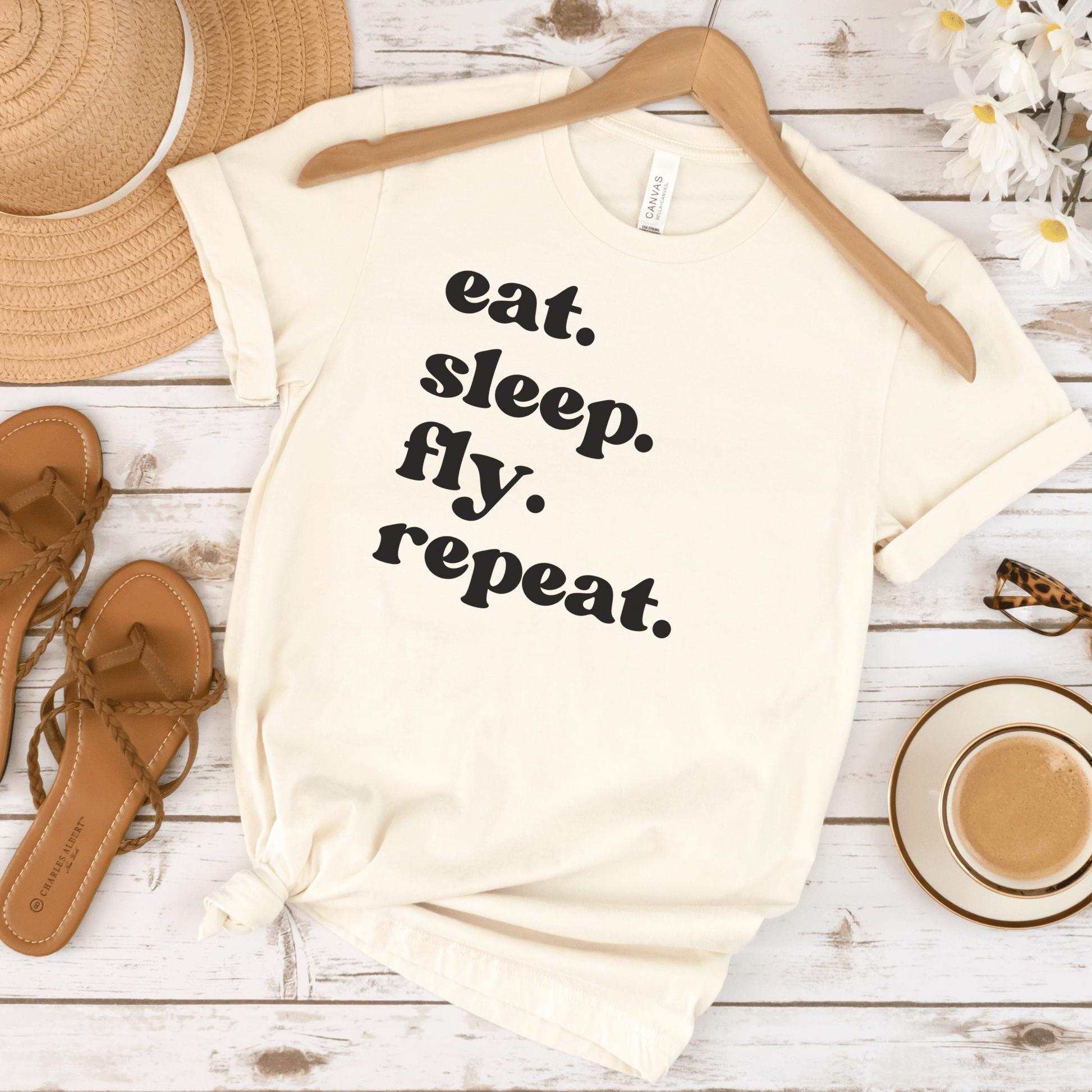 beige unisex wanderlust t-shirt that says eat. sleep. fly. repeat.