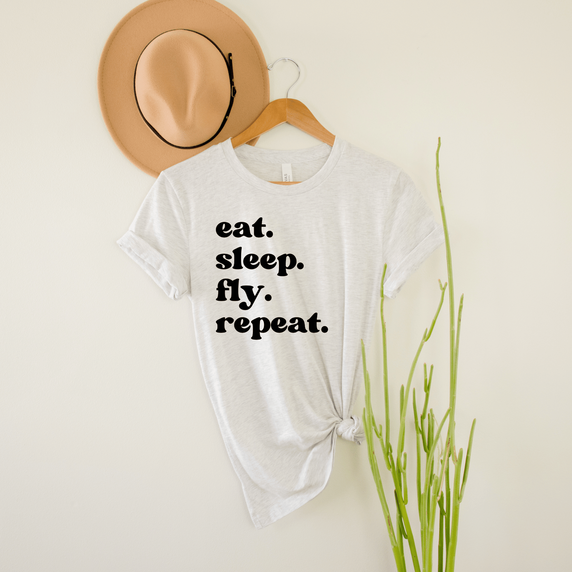 light gray unisex wanderlust t-shirt that says eat. sleep. fly. repeat.